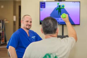 Physical Therapist with resident lifting dumbbells